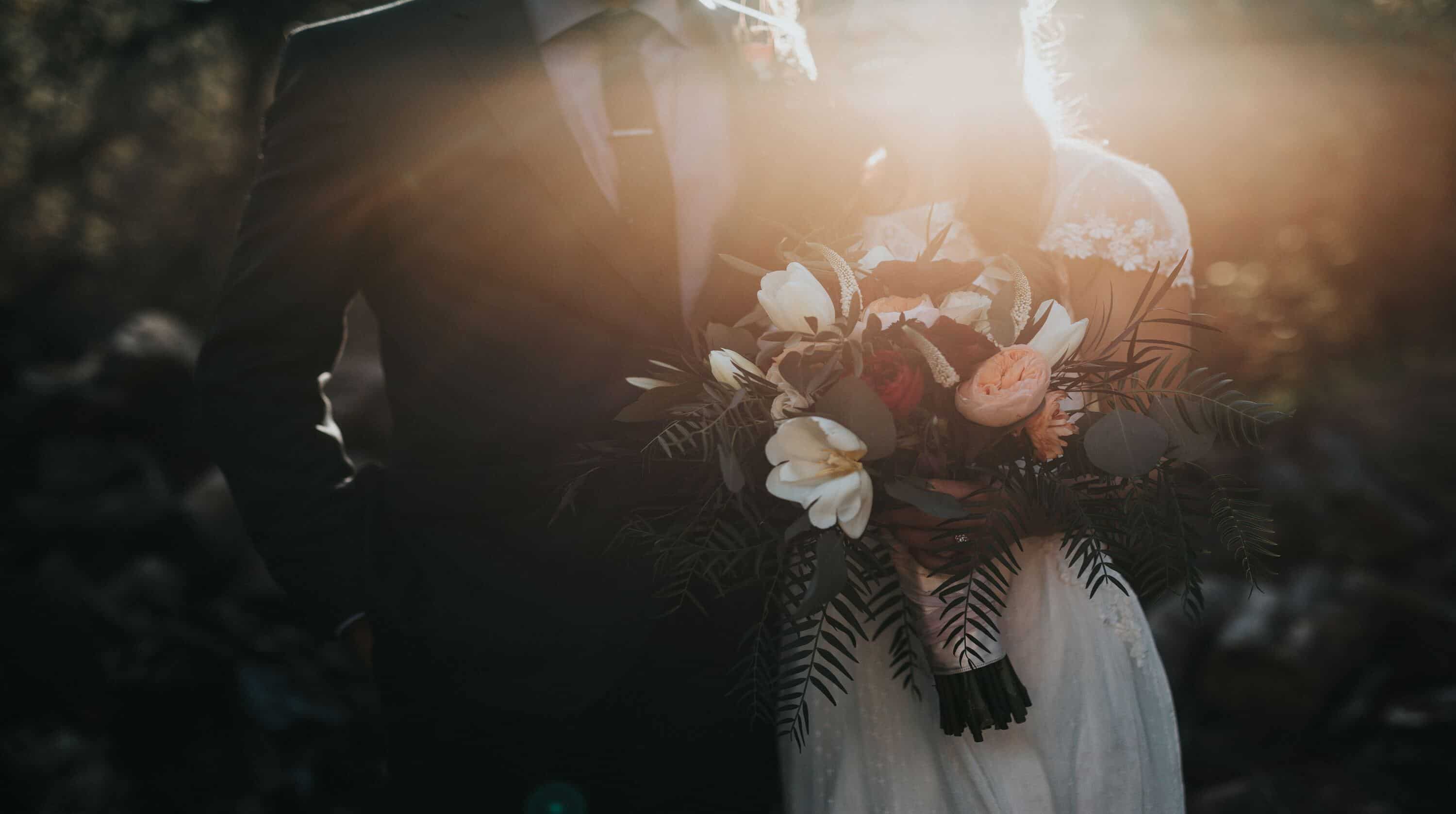 A couple is dressed for a wedding and the bride is holding a bouquet.