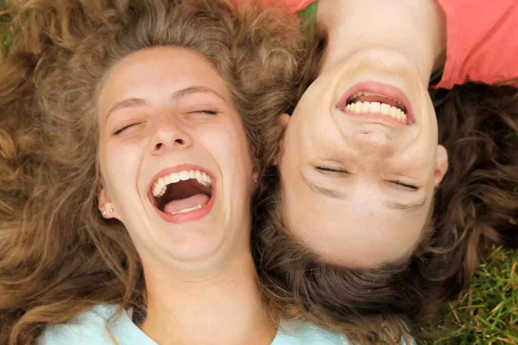 Christian friendship between two teenaged girls laying on the ground laughing