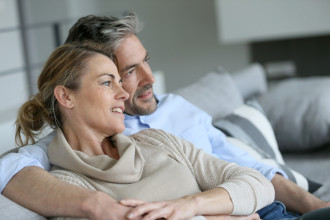 Middle-age couple sitting on a couch looking together at something