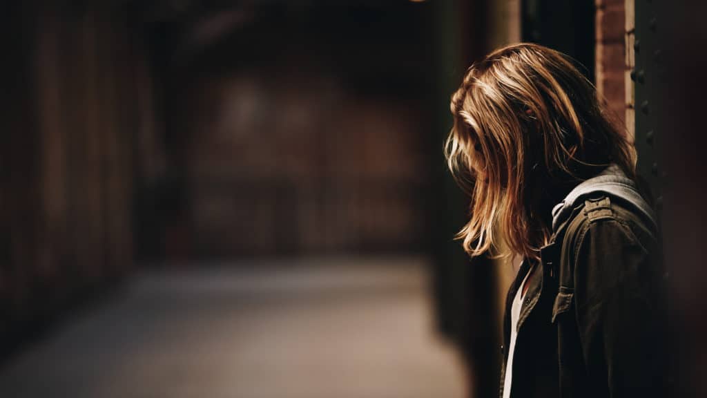 A woman looks toward the ground. Her hair is covering her face.