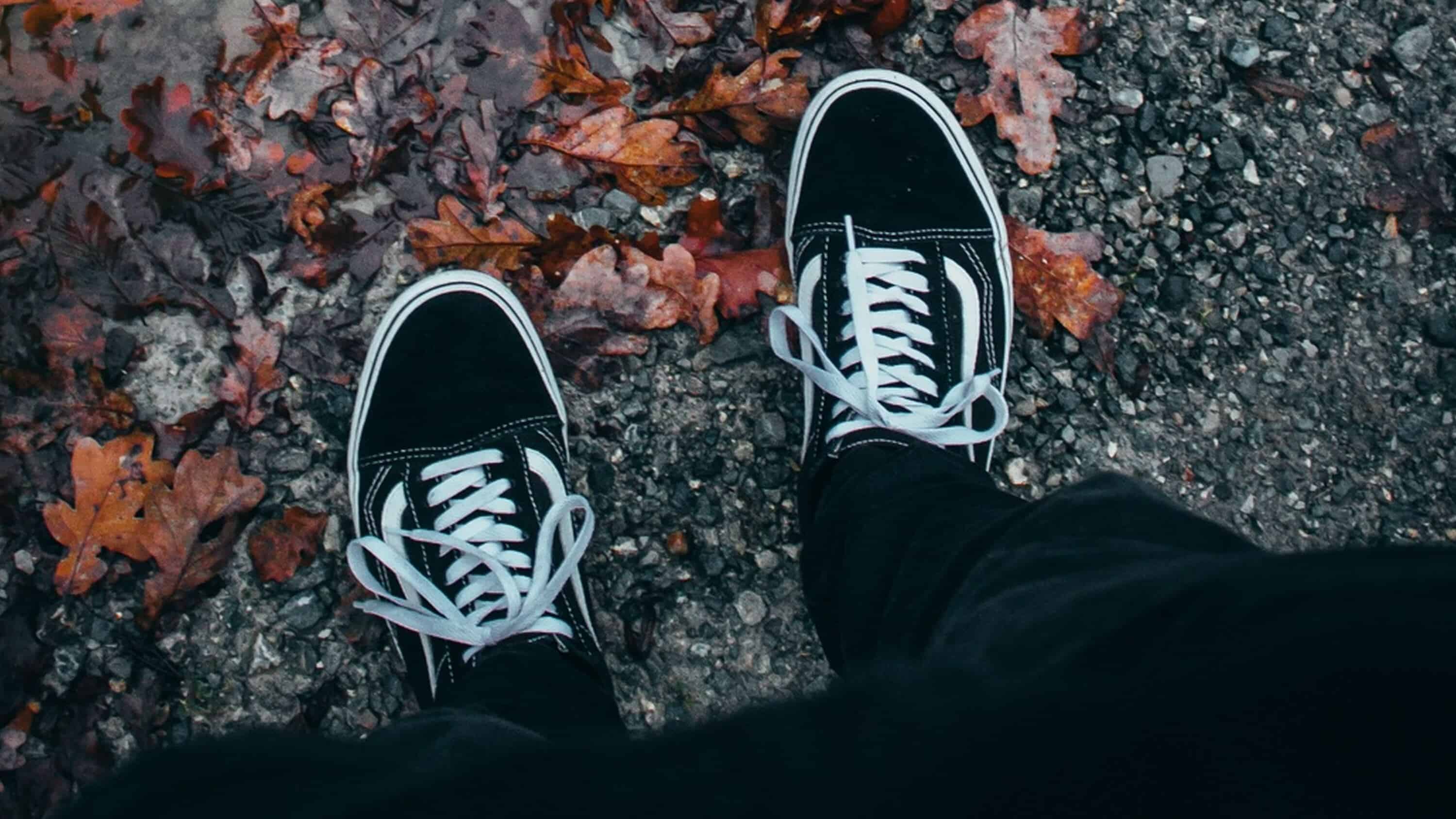 person standing in black and white shoes in leaves