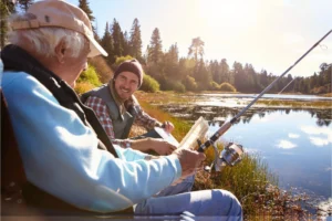 Father and adult son fishing on the bank of a river
