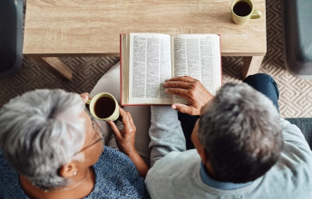 Seated elderly couple reading the Bible