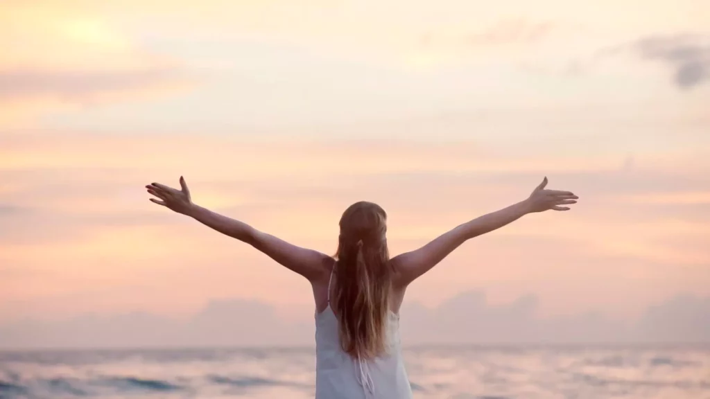 photo of woman with outstretched arms at sunset. She wears white because she knows what sex is worth to marriage and to God.