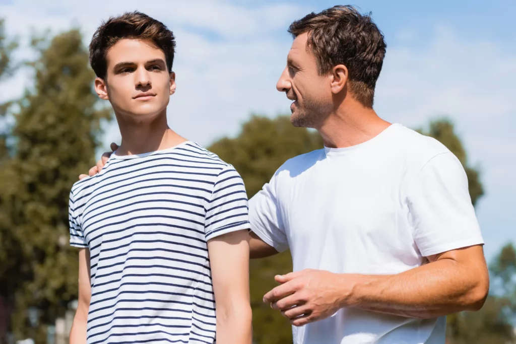 adult son and father talking and walking together with the father's hand on his son's shoulder