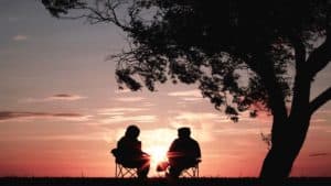 silhouette of couples sitting by a tree