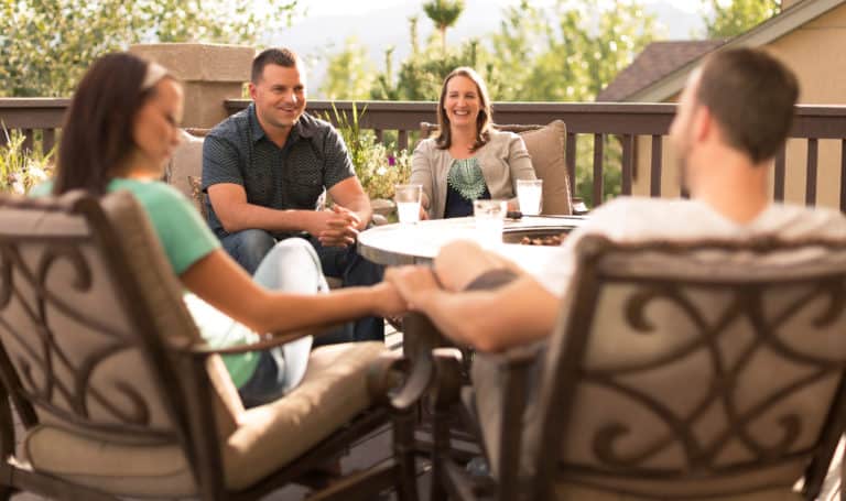 A couple in thier late 30's talk with a couple in thier early 20's on a back porch.