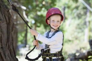 Boy with helmet and in harness for climbing trees