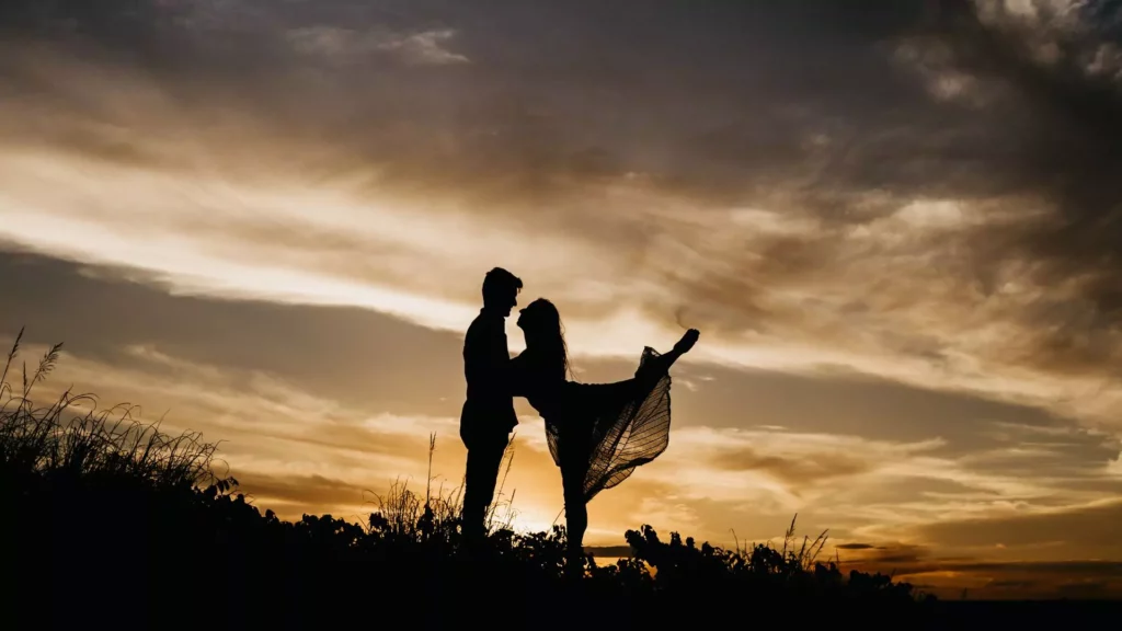 “A couple shares a romantic moment at sunset, silhouetted against a dramatic sky, embodying the idea of what the Bible says about soulmates.”