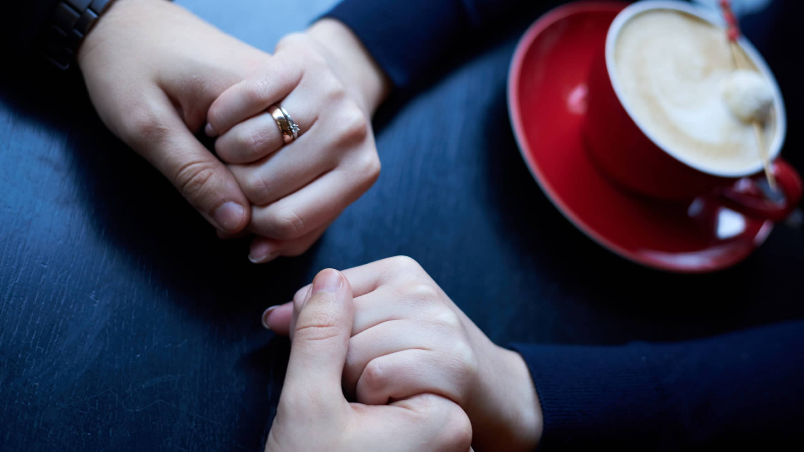 couple holding hands over coffee cup