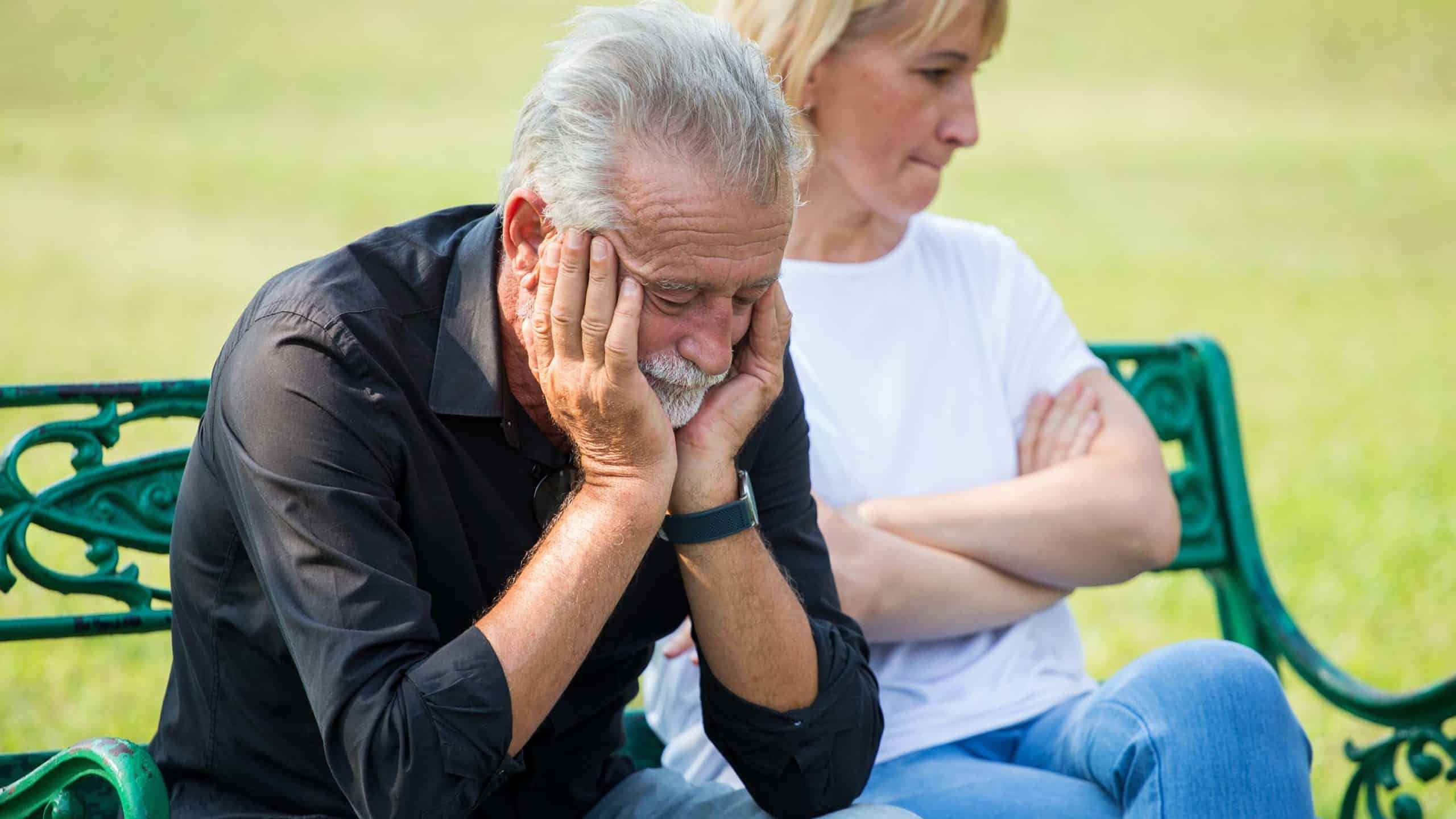 Older husband looking distressed next to wife