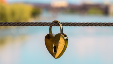 Heart lock on steel cable in front of lake