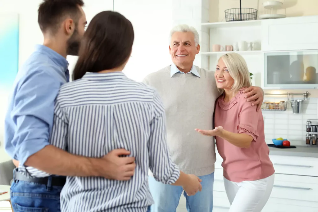 A young couple in a kitchen talking to their in-laws. Controlling in-laws trying to run your life is a difficult challenge.