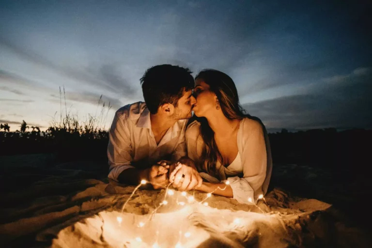 A romantic couple kisses under twilight with warm lights surrounding them, evoking King Solomon’s line on premarital sex about not awakening love before its time.