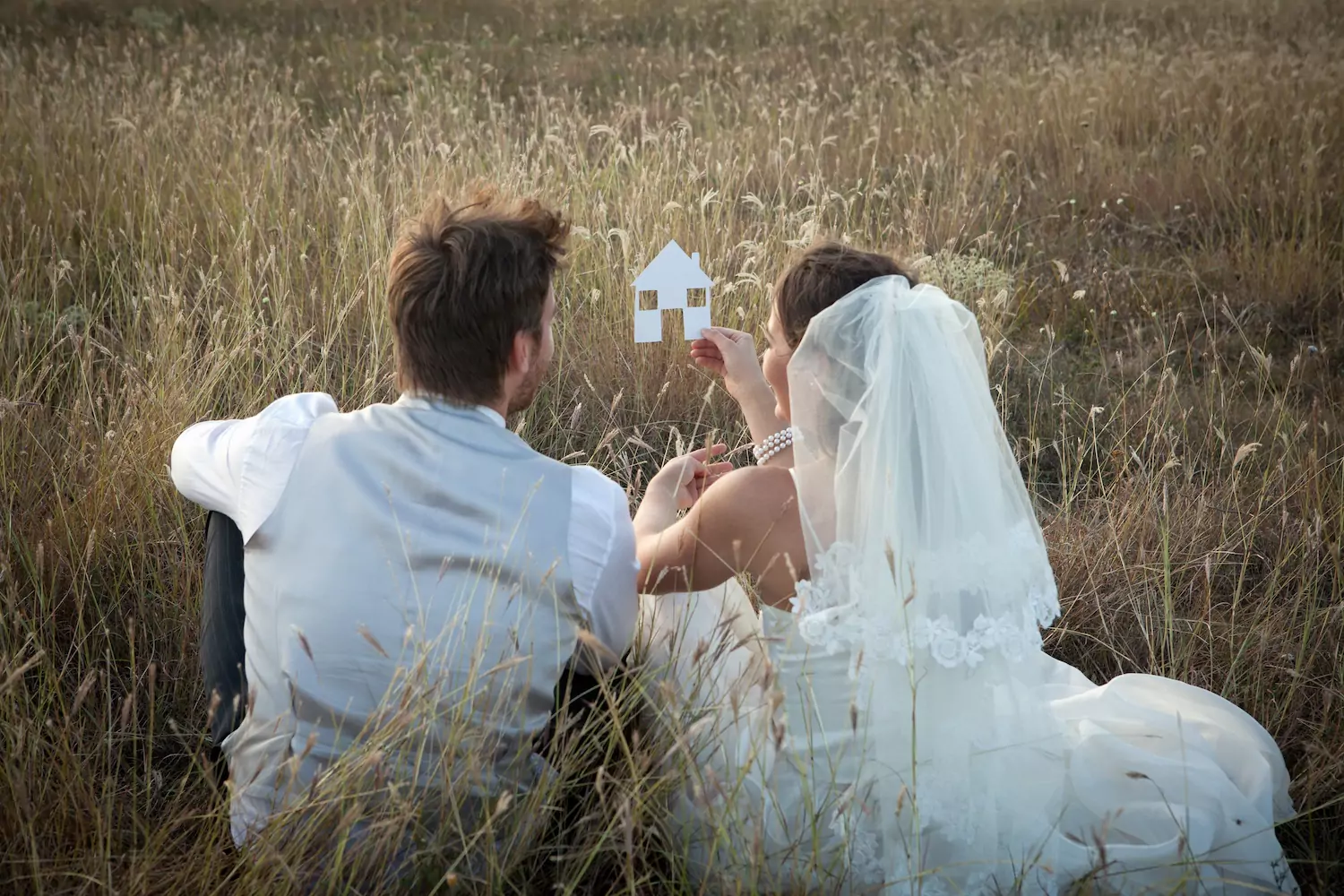 A young bride and groom sit in a field, holding a cut-out of a house, signifying their marriage hopes and dreams. But what if your marriage is not meeting your expectations?
