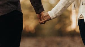 A couple holds hands on an autumn afternoon.