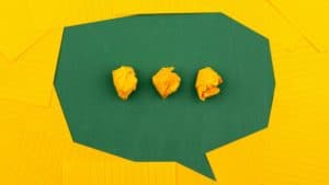 three crumpled pieces of yellow paper in green paper speech bubble