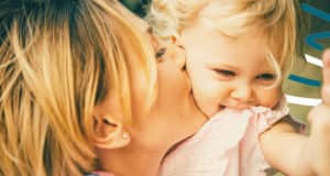 Mother kissing daughter's cheek in a show of love