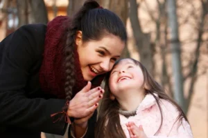 Mom and young daughter smiling as they pray