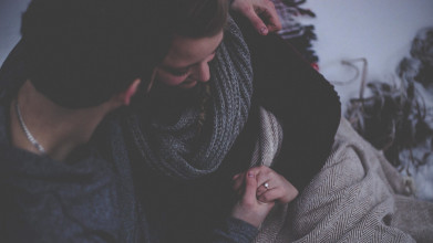 husband and wife holding each other beneath blanket