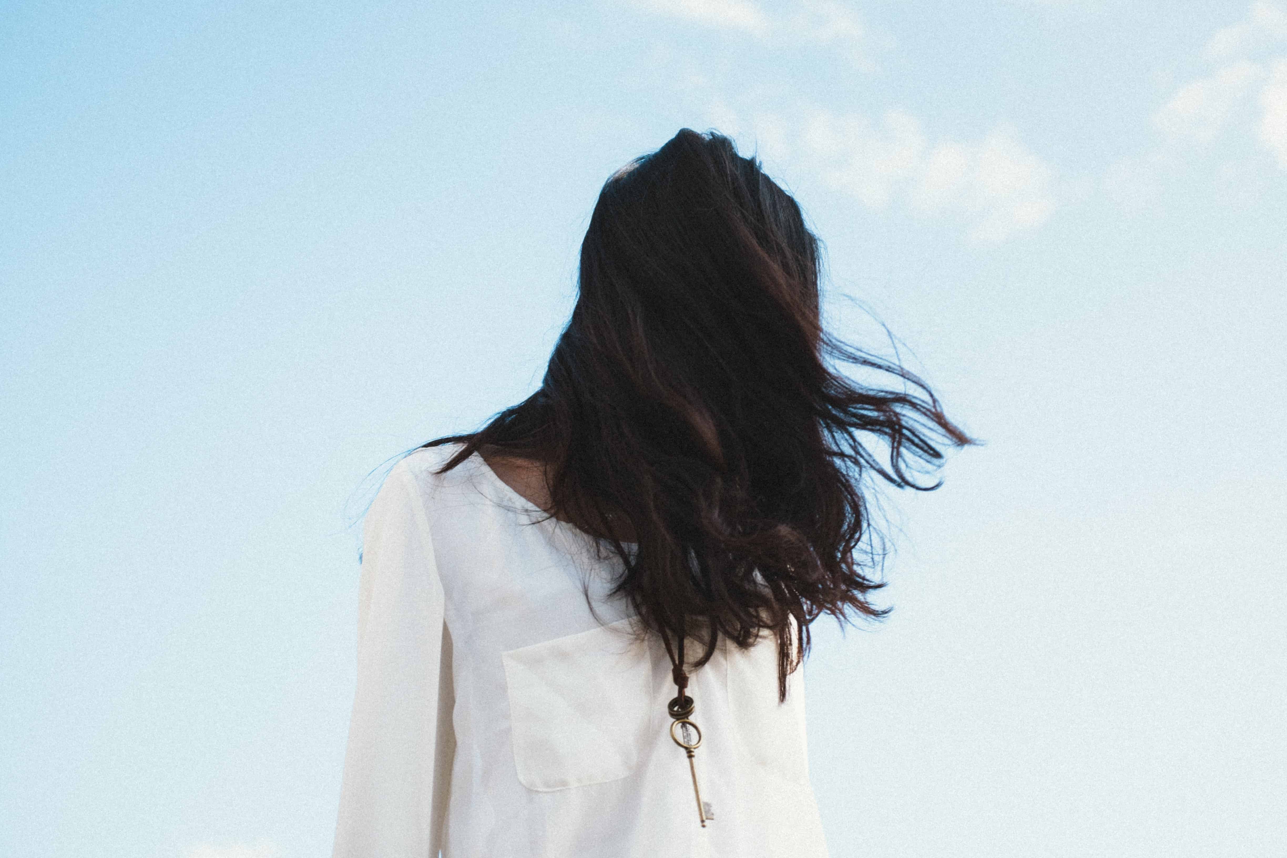 Young woman standing outside, her face hidden by her hair