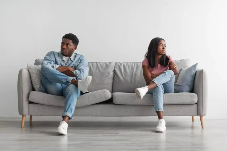 A man and a woman sit on a long couch, refusing to look at each other. Avoiding Conflict in Marriage is not healthy for your relationship.