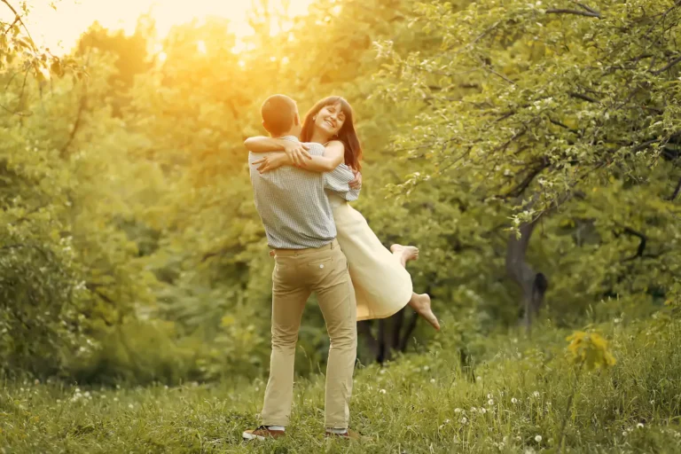 A happy couple embraces in a field at sunset. Building trust in marriage is imperative to a successful relationship.