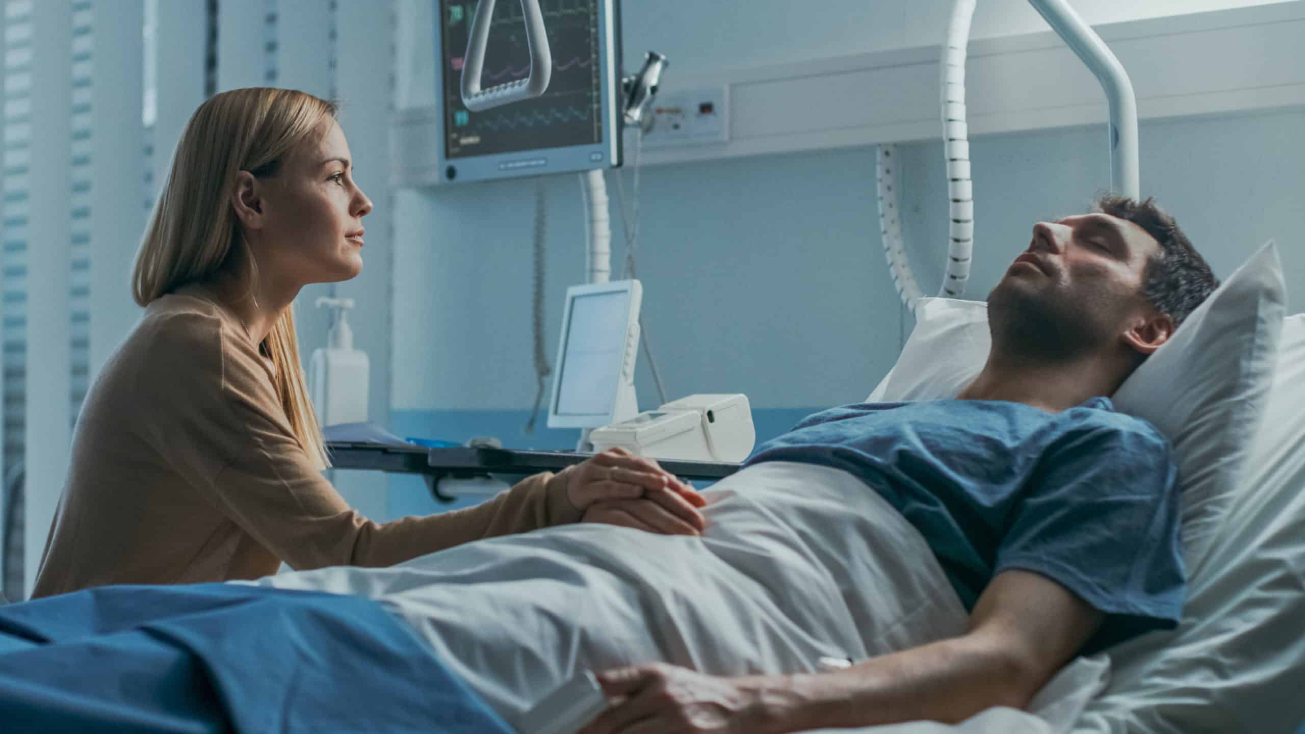 Wife holds sick husband's hand in hospital
