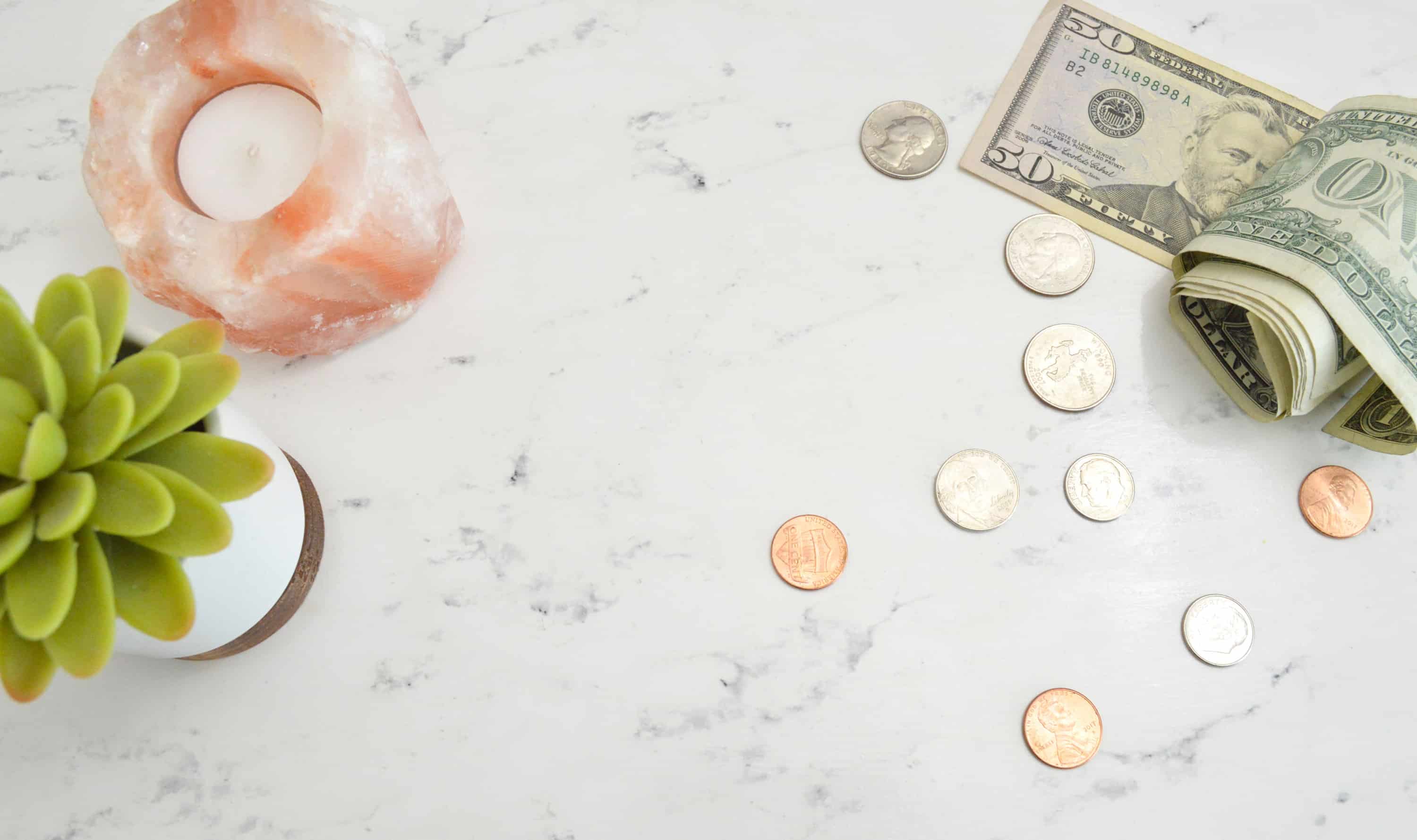 A picture of a marble table top with loose change and dollar bills spread about.