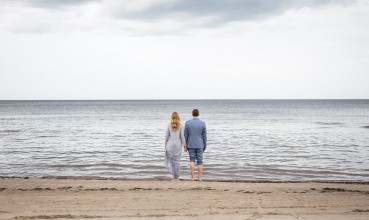 A couple holds hands while looking at the ocean.