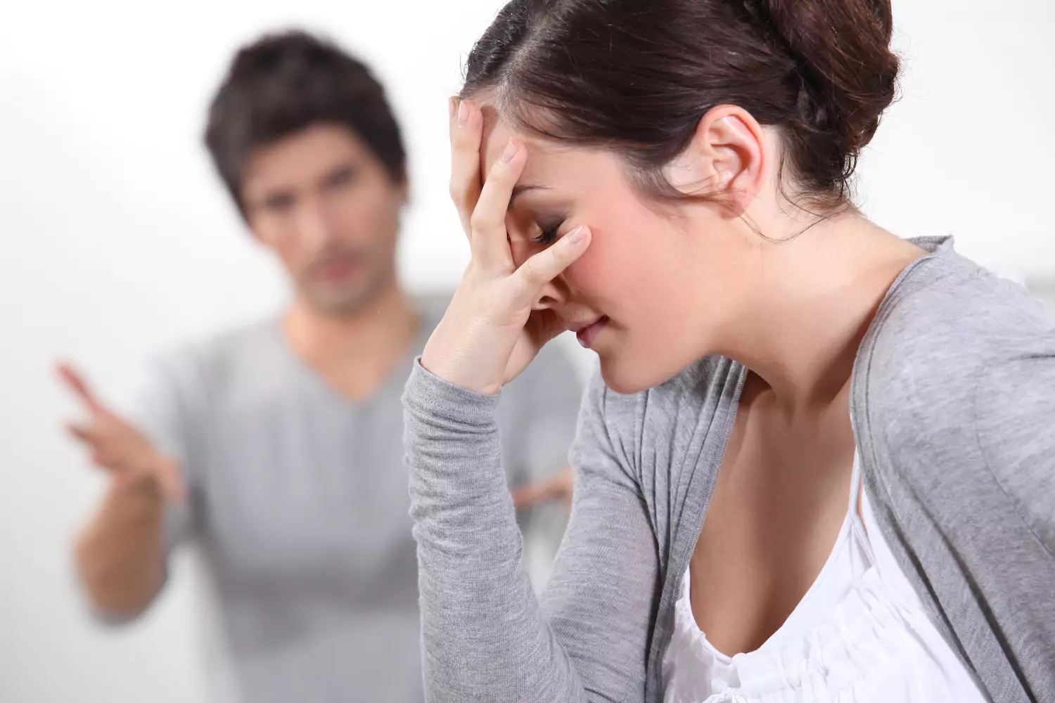 A young couple looking to resolve a conflict in their marriage. The man tries to explain as the wife covers her face in frustration.