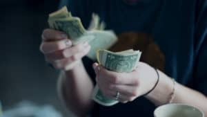 A married woman is counting dollar bills in her hands.