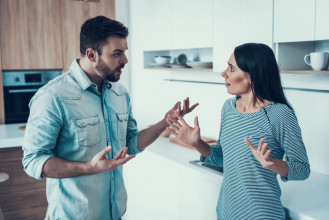 Couple standing in their kitchen having a tense discussion