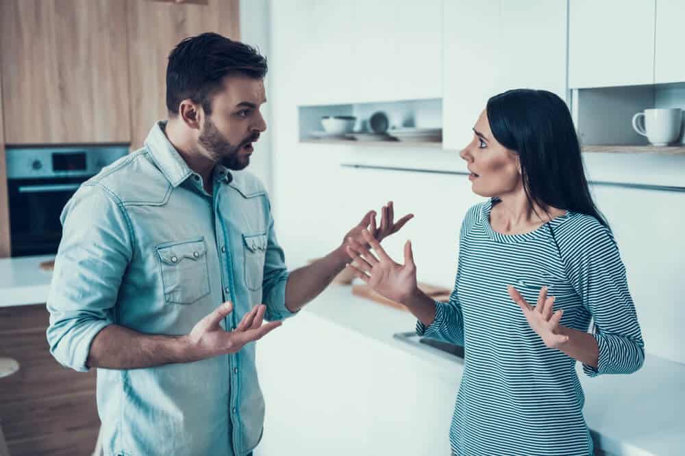 Couple standing in their kitchen having a tense discussion