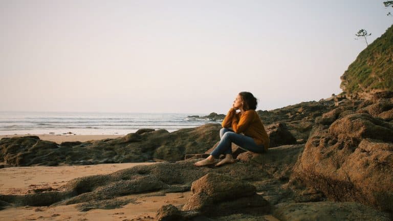 women sitting on rocks near beach