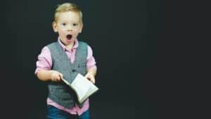 blonde little boy shocked expression holding open book