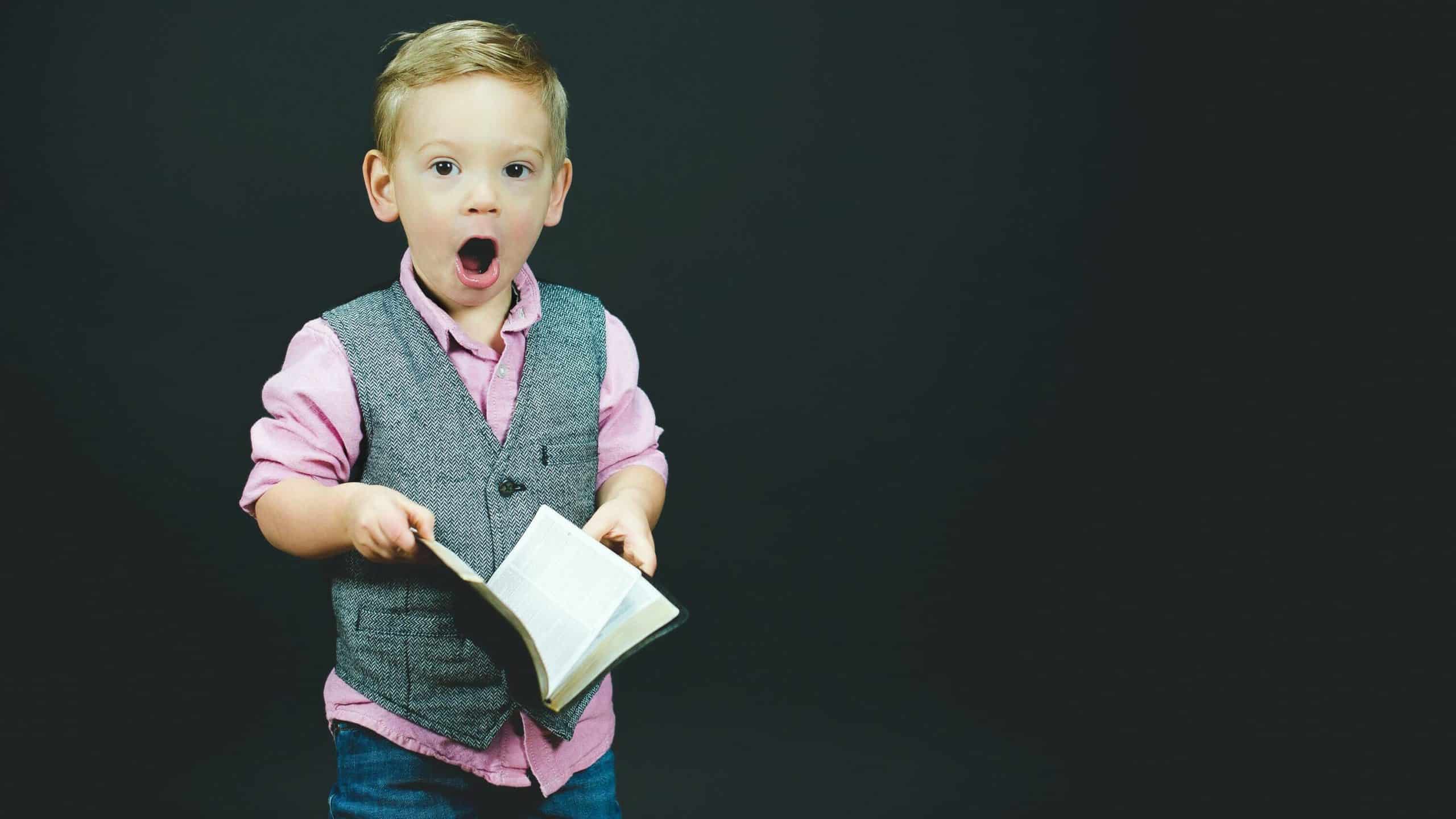 blonde little boy shocked expression holding open book
