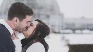A married couple kisses in the snow.