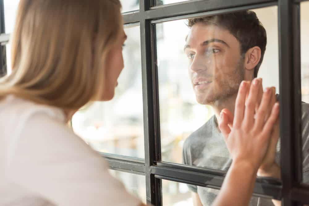 Young couple looking at each other through a window