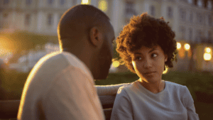 black couple sit on park bench looking into each other's eyes