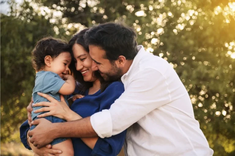 A family outdoors, parents hugging young child