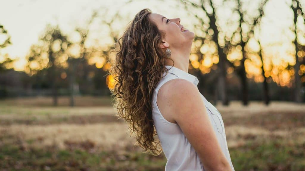 woman in white shirt standing in field smiling