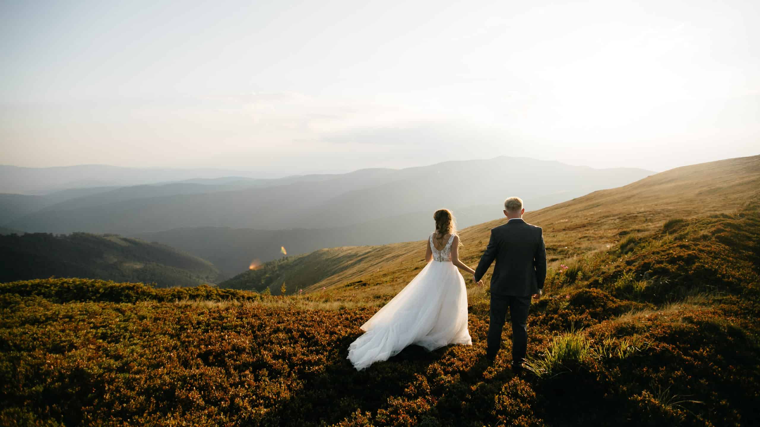 Newlywed husband and wife looking out into a mountain sunset