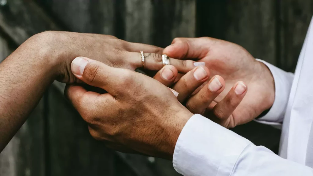 A man slips a wedding ring onto his bride's finger. They are making a marriage covenant before God, based on the Bible.