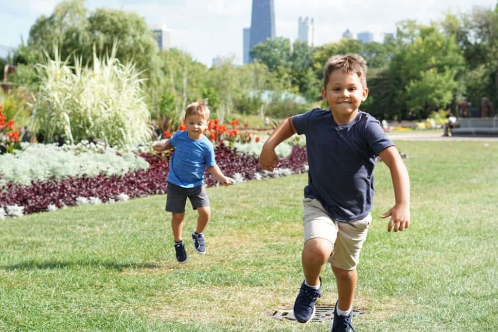 Two young boys running in a park on a sunny Summer day