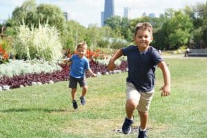 Two young boys running in a park on a sunny Summer day