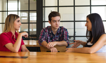 two women and a man talking at a table