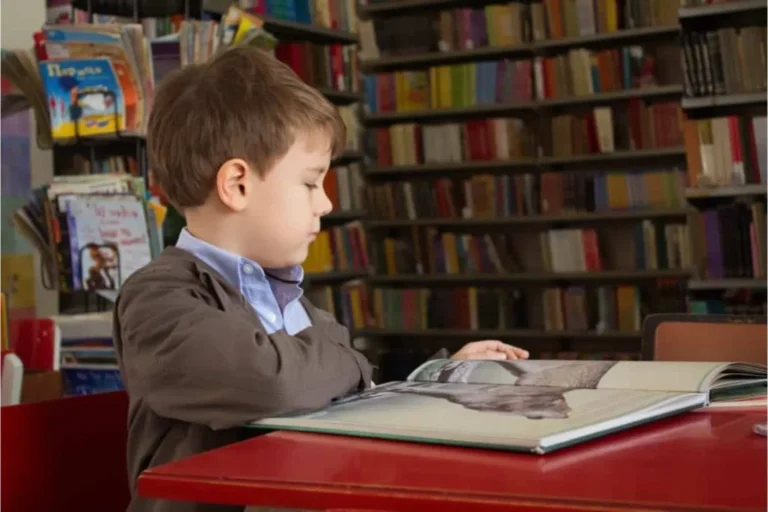 Boy reading a book at a table in a library