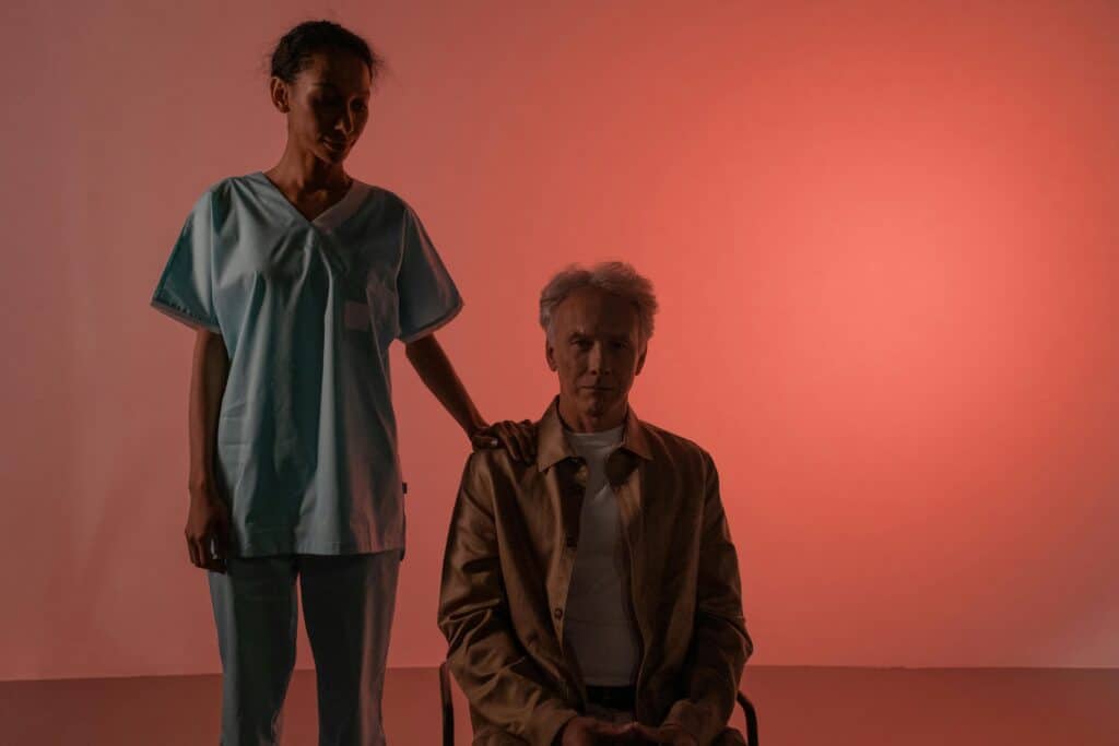 older man in wheelchair doctor or nurse hand on his shoulder red light