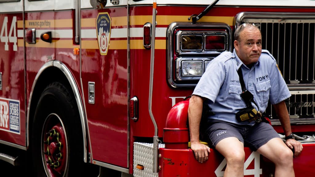 a fireman sits on the bumper of a fire truck